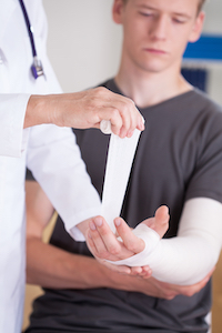 Doctor wrapping young man's arm to help with a fracture